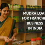 Indian woman in a mustard saree smiling while counting currency inside a herbal product shop, with the overlay text “Mudra Loan for Franchise Business in India” in bold sans-serif font on a semi-transparent dark box.