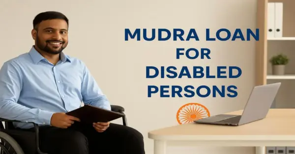 A confident Indian man in a wheelchair wearing a light blue shirt sits at a desk with a laptop, smiling while holding a portfolio. Text on the wall reads 